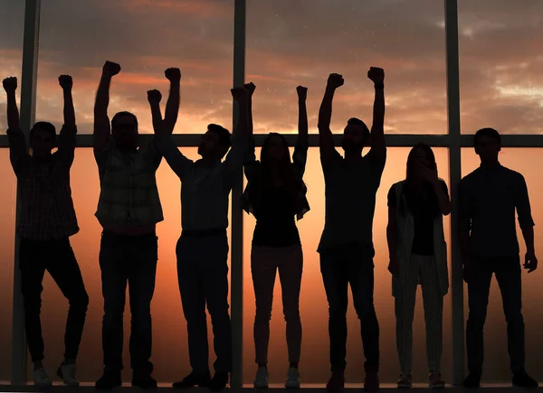 Equipe de negócios de pé perto da janela com as mãos para cima — Fotografia de Stock