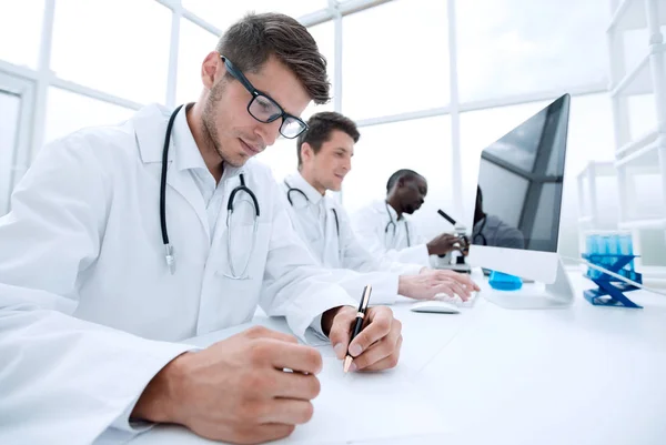 Group of scientists sitting at the laboratory table — Stock Photo, Image