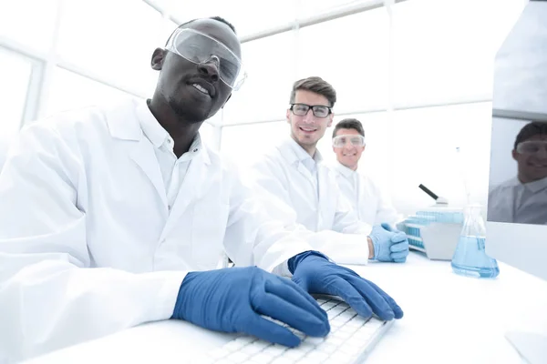 Группа ученых, сидящих за лабораторным столом — стоковое фото