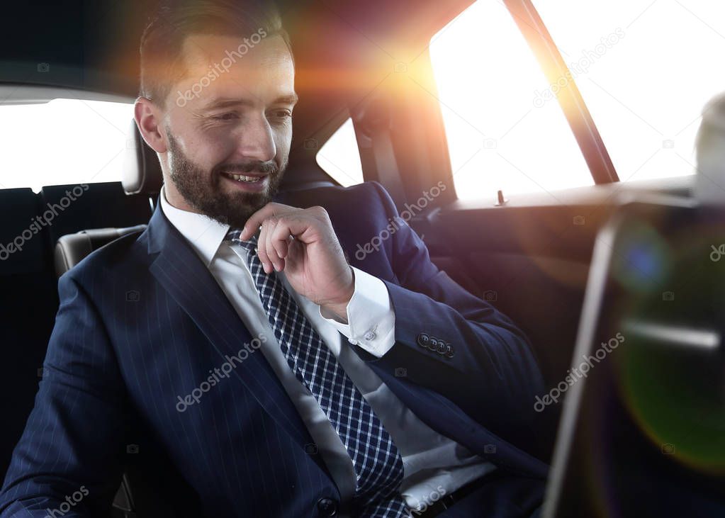 businessman reads information on laptop while sitting in car