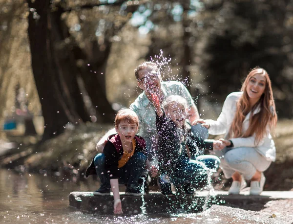 Ouders spelen met kinderen in de buurt van het meer in de stad Park — Stockfoto