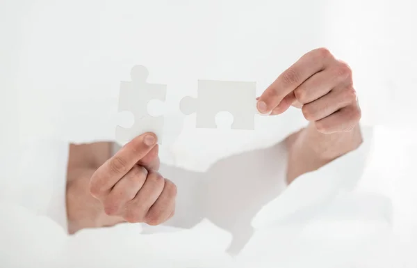 Mann verbindet Puzzleteile und zerbricht die Wand aus Papier. — Stockfoto