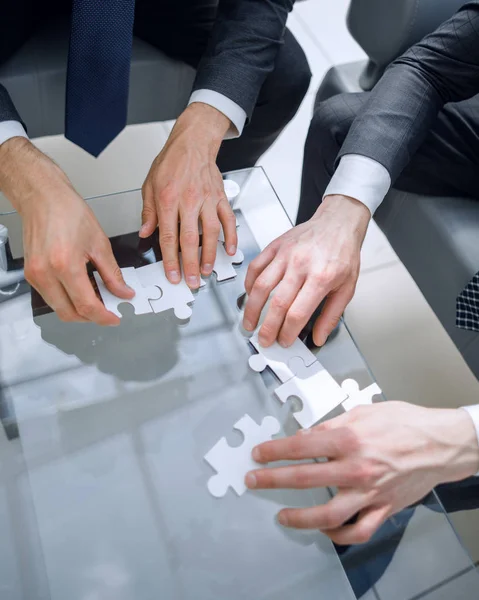 Close up.business people putting together a puzzle ,sitting behind a Desk — Stock Photo, Image