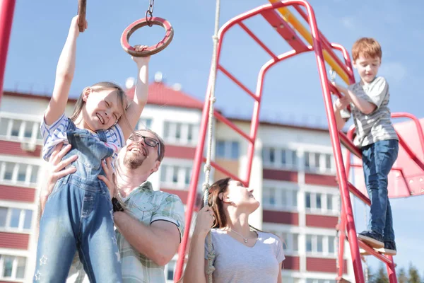 Ung familj med barn som leker på lekplatsen — Stockfoto