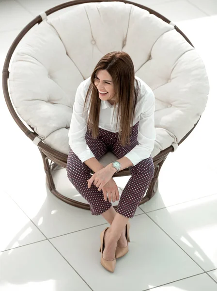 Stanca giovane donna seduta in comoda sedia rotonda — Foto Stock