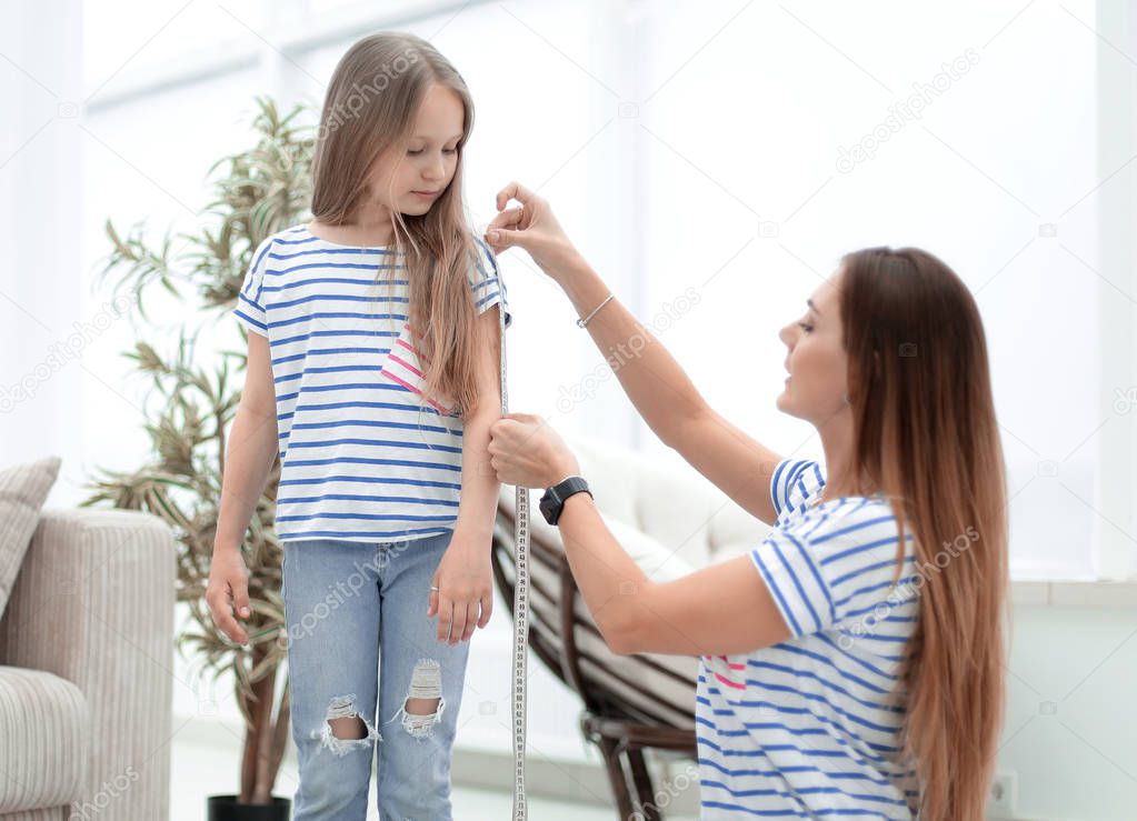 attentive mother and daughter make measurements for new clothes