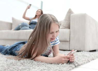 Anne ve kızı onların akıllı telefonlar yeni oturma odasında kullanarak.