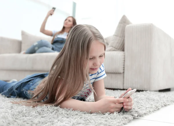 Mãe e sua filha usando seus smartphones na nova sala de estar . — Fotografia de Stock