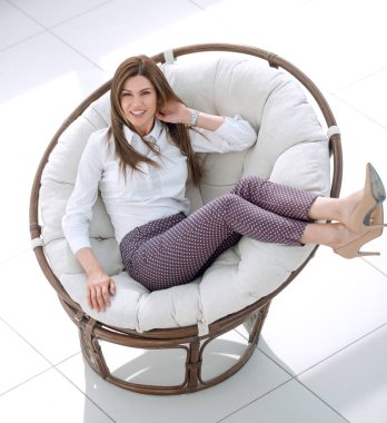 gülümseyen rahat yuvarlak sandalyede oturan kadın