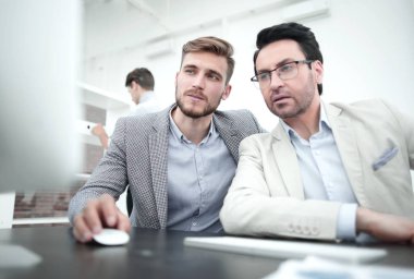 İki işadamı yeni bilgi almak için bir bilgisayar kullanıyor.