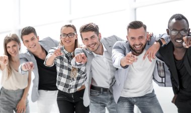 Bir grup insan kamerayı işaret ediyor ve gülümsüyor.