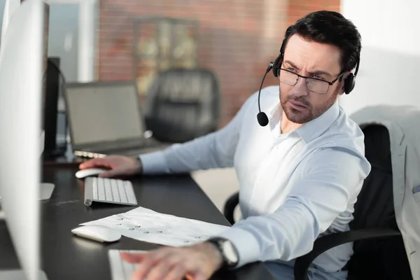 Close up.businessman con un auricolare seduto alla sua scrivania — Foto Stock