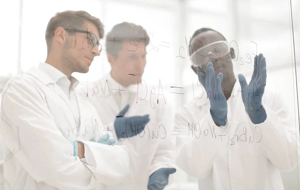 Groupe de scientifiques parlant debout près d'un panneau de verre . — Photo