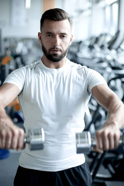 Close up.stylish jeune homme travaillant avec des haltères dans la salle de gym . — Photo