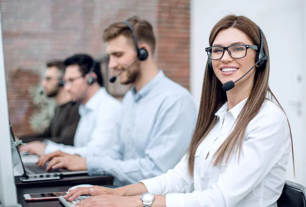 Leende call center medarbetare sitter vid sitt skrivbord — Stockfoto