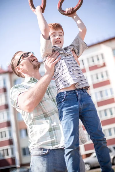 Father helps his son to catch up on the bar — Stock Photo, Image