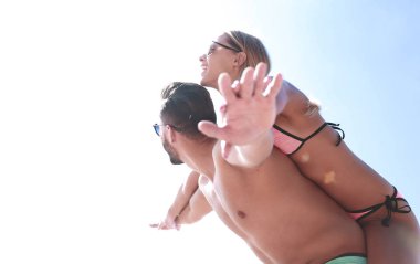 Kumsalda kadını sırtında taşıyan bir adam..