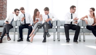 Grup Genç çalışanların iletişim ofis lobisinde oturan
