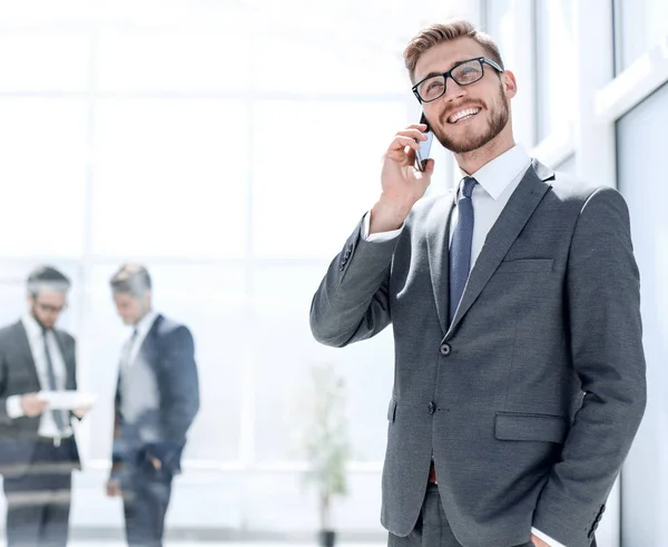 Hombre de negocios con teléfono móvil de pie junto a la oficina del Banco — Foto de Stock