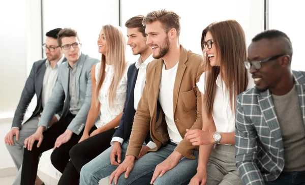 Grupo de jóvenes profesionales sentados cerca de la pared — Foto de Stock