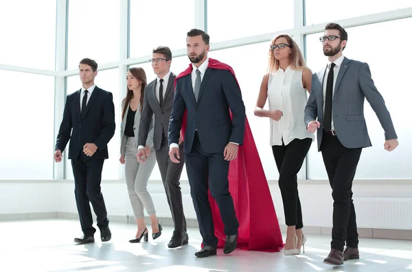 businessman in Superman cloak and business team standing in office lobby