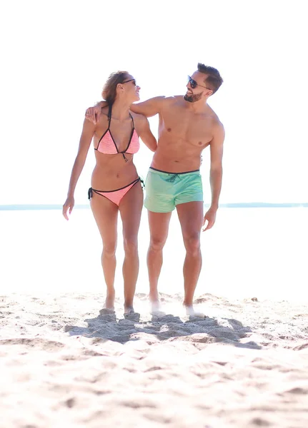 Pareja joven cogida de la mano y caminando en la playa. — Foto de Stock