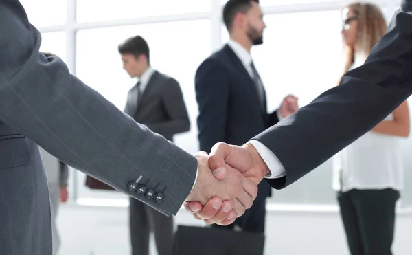 Stäng up.handshake business partners i bakgrunden av den av — Stockfoto