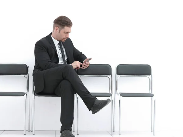 Homme d'affaires avec mobile assis dans le couloir du bureau — Photo