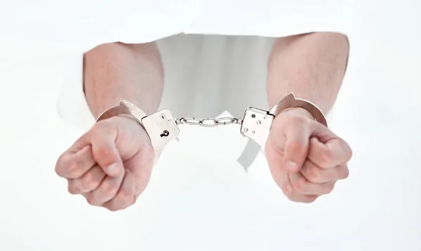 Handcuffs on the hands of a man breaking a paper wall — Stock Photo, Image