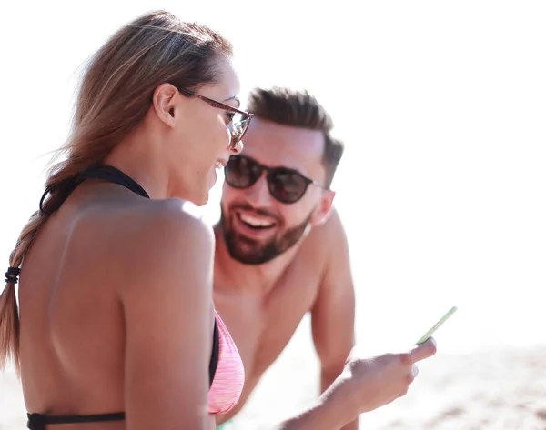 Lächelndes Paar beim Stöbern auf Fotos am Strand — Stockfoto