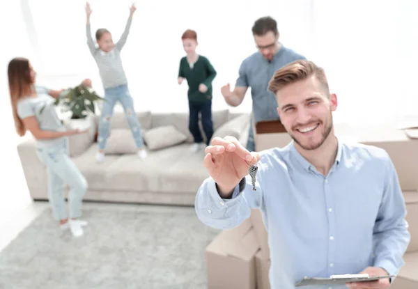 Sonriente agente inmobiliario con llaves en el fondo de un nuevo apartamento — Foto de Stock