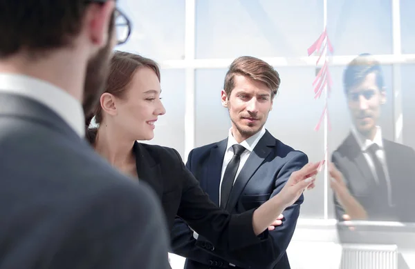 Close up.employees discussing sticky notes on a glass Board — Stock Photo, Image