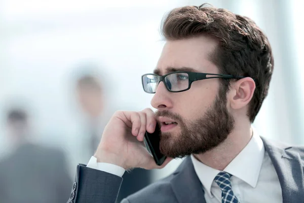 Бизнесмен разговаривает на смартфоне на офисном фоне — стоковое фото