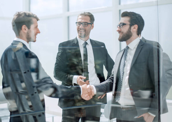 business partners shaking hands in the lobby of the business cen