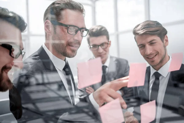 Compañeros de negocios leyendo notas adhesivas sobre vidrio —  Fotos de Stock