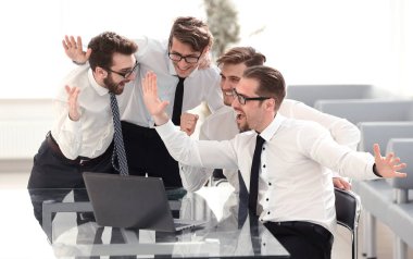 Mutlu iş ekibi dizüstü bilgisayara bakıyor.