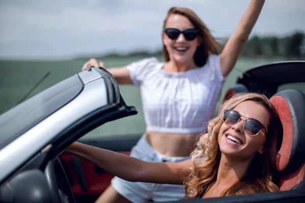 행복 한 젊은 여성 2 명 이 컨버터블 카를 타고 있습니다 — 스톡 사진
