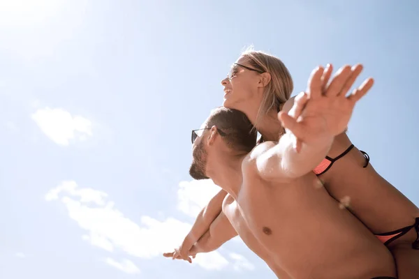 Mężczyzna niesie kobietę na barana na plaży. — Zdjęcie stockowe