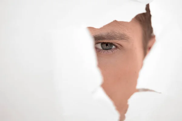 De près. homme d'affaires regardant à travers un trou dans le mur de papier — Photo