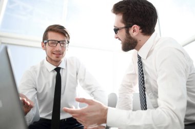 çalışanların açık bir dizüstü bilgisayar önünde oturup bir şey tartışmak.