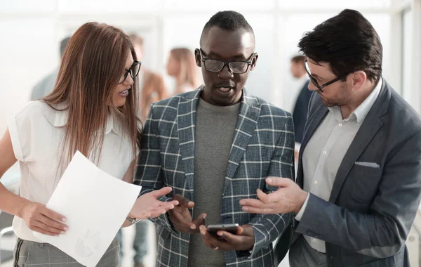 Tres colegas mirando la pantalla del teléfono inteligente — Foto de Stock