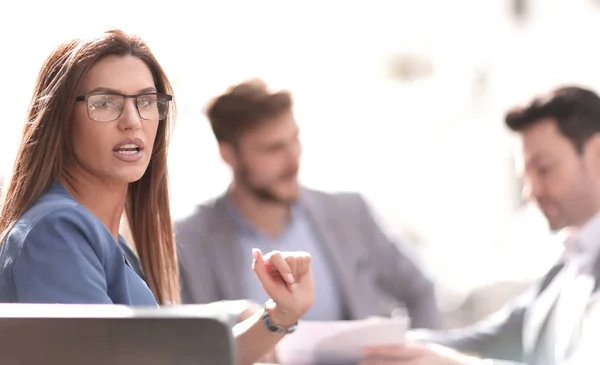 Mujer de negocios sentada en una mesa en el fondo de los colegas — Foto de Stock