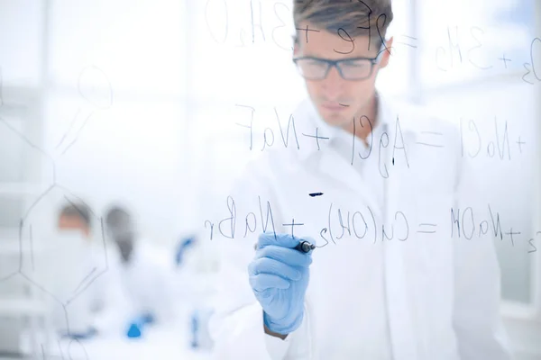 Vážnou vědec píše chemický vzorec na skleněné desce. — Stock fotografie