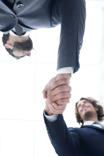 Vista dal basso di due uomini che stringono la mano in piedi — Foto Stock