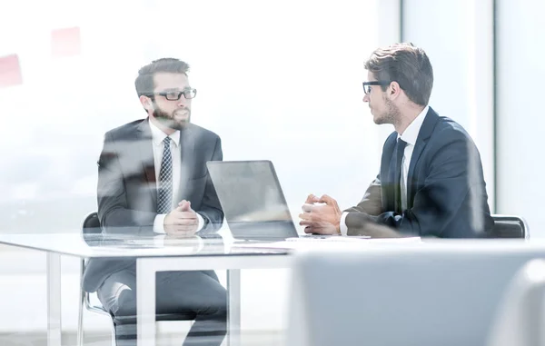 Twee zakenmensen praten zittend aan een bureau — Stockfoto