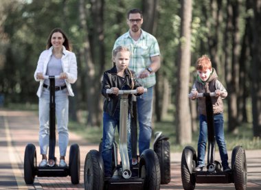 parkta bir elektrikli mini hoverboard sürme iki çocuklu aile.