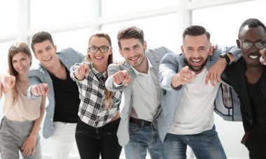 Bir grup insan kamerayı işaret ediyor ve gülümsüyor.