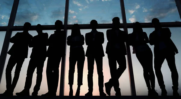 Silhouette di un gruppo di uomini d'affari in piedi vicino alla finestra dell'ufficio — Foto Stock