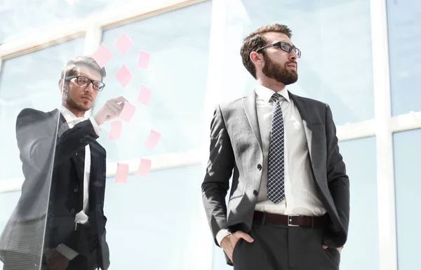 Mitarbeiter stehen in der Nähe einer transparenten Bürowand — Stockfoto