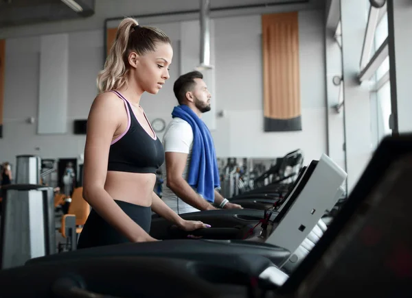 Hermosos deportistas trabajan en la cinta de correr en el gimnasio — Foto de Stock